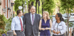 Luke Clippinger, wearing a grey suit, talks with constituents. A man is on his right, two women on his left.